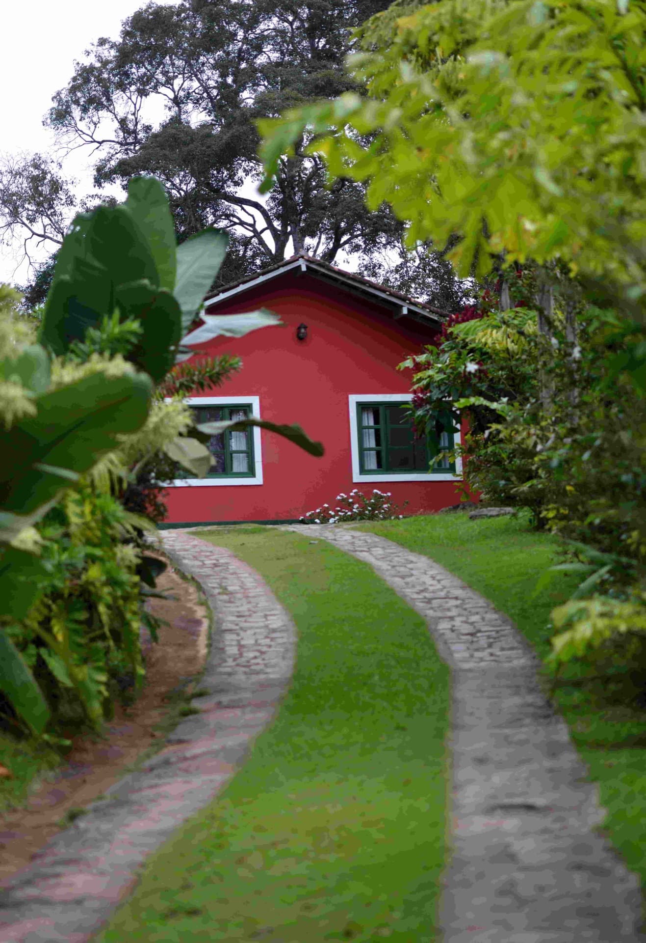 Caminho de pedras entre o jardim até a casa principal da pousada