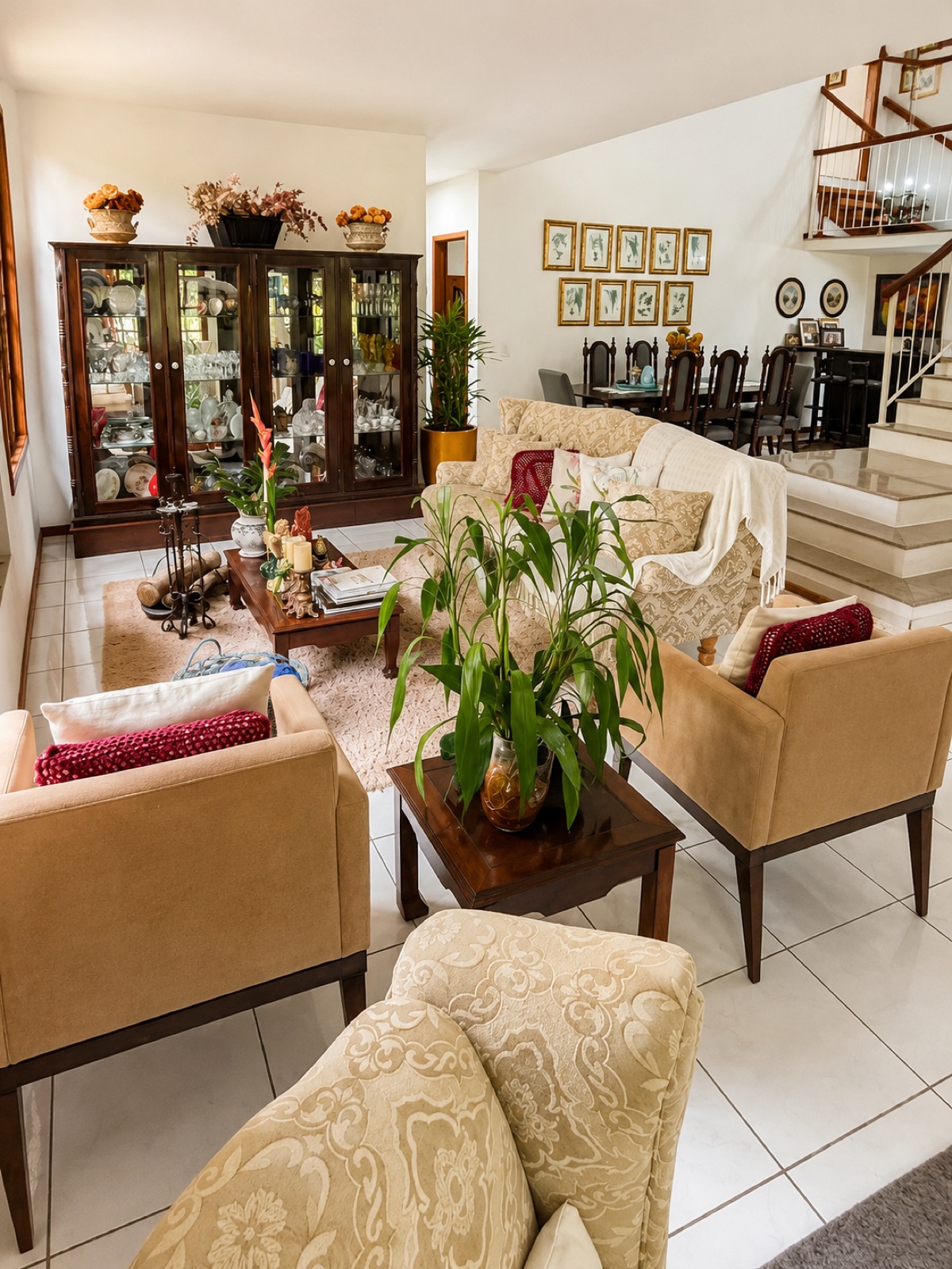 Sala de estar da Pousada Valle di Trento com poltronas, plantas e escada de madeira